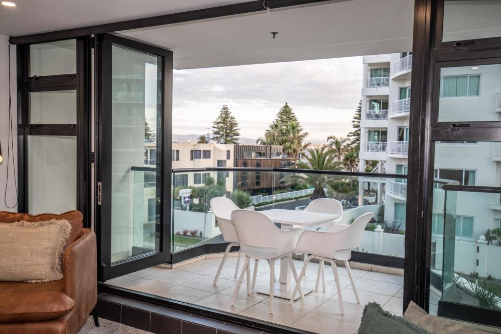 a balcony with white chairs and a table and a view at Ocean Eleven 22 in Mount Maunganui