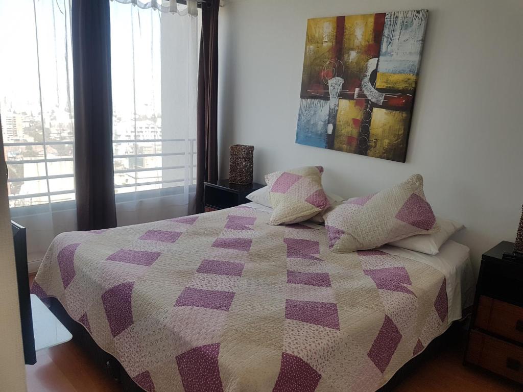 Departamentos Pontoni في سانتياغو: غرفة نوم مع سرير مع لحاف أرجواني وبيض