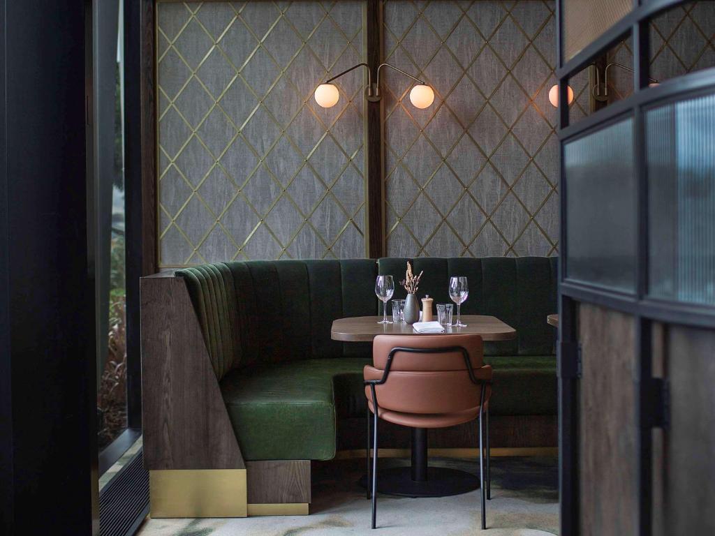 a small table and a green couch in a restaurant at Novotel Auckland Airport in Auckland