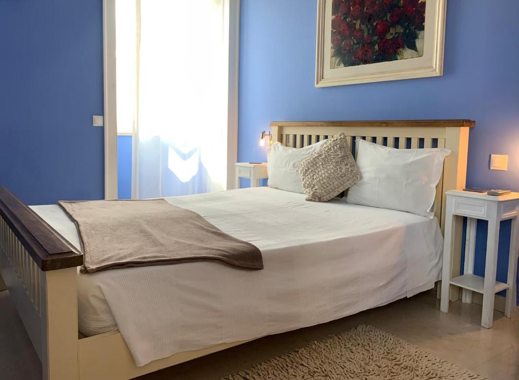 a blue bedroom with a bed with white sheets and pillows at Residence Lagos in Lagos