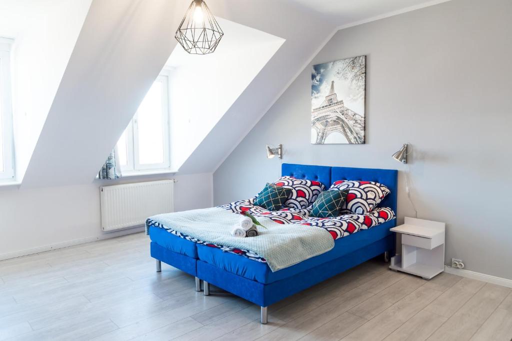 - un lit bleu dans une chambre blanche avec la tour eiffel dans l'établissement Apartments Wyszyńskiego, à Szczecin