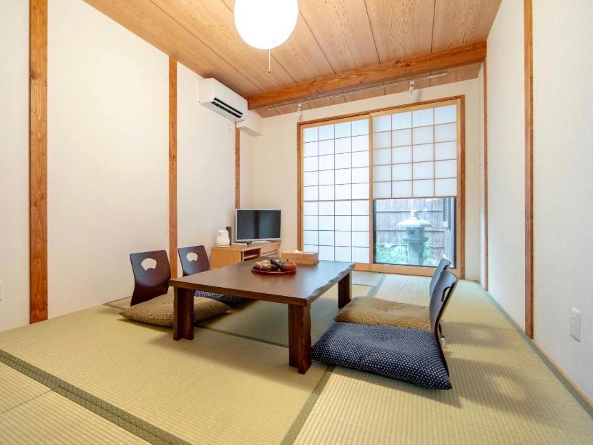 ein Wohnzimmer mit einem Holztisch und Stühlen in der Unterkunft Tsurui Nijo 鶴居二条 in Kyoto