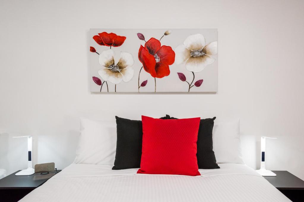 a bedroom with a white bed with a red pillow at Euroa Motor Inn in Euroa