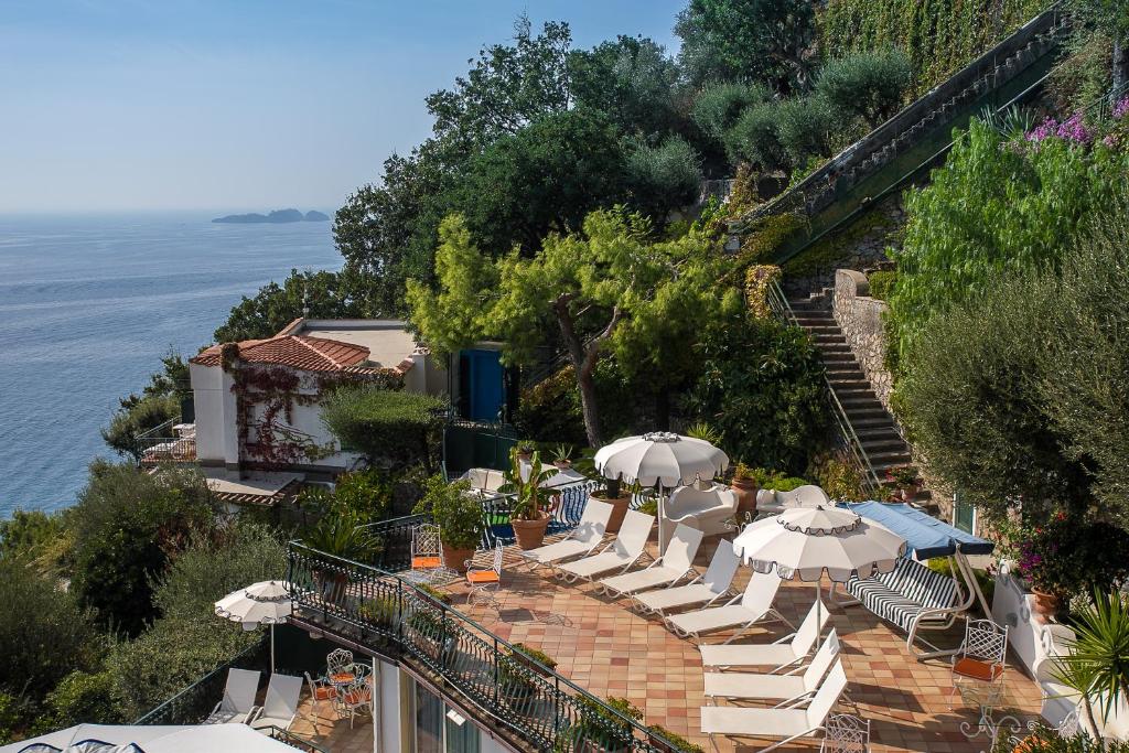 een groep stoelen en parasols op een heuvel naast het water bij Luxury Villas Positano in Positano