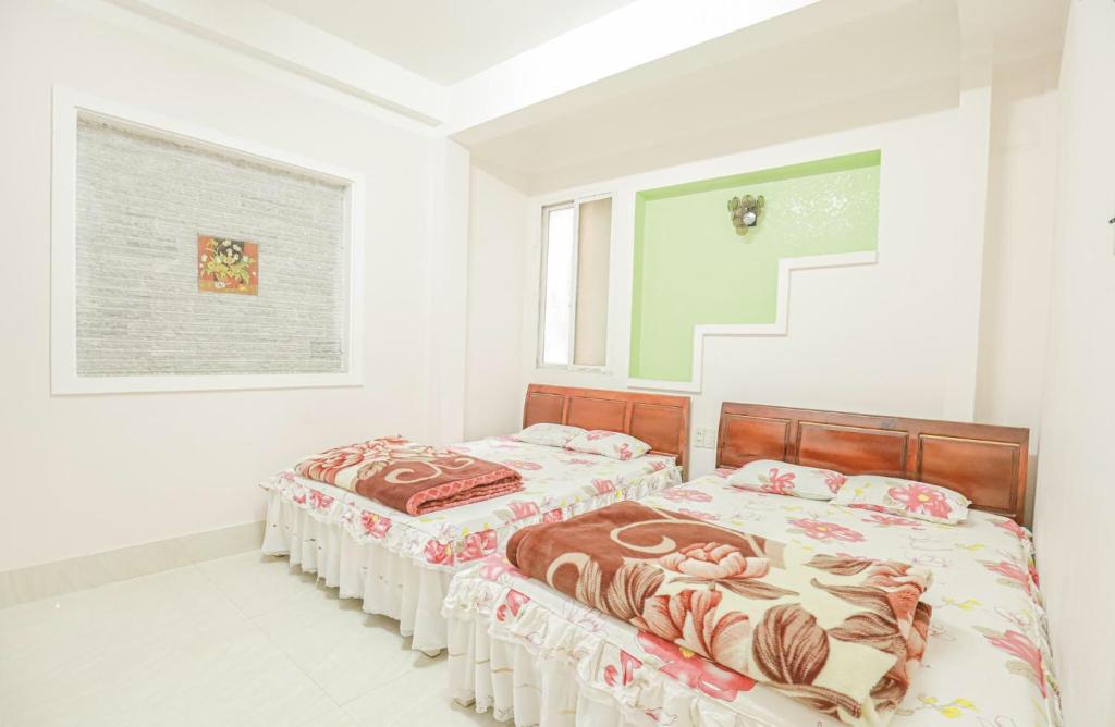 two beds in a room with white walls at Minh Chiến Hostel -Guest House- in Da Lat