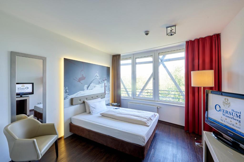 a bedroom with a bed and a tv and a chair at Hotel Oversum Winterberg Ski- und Vital Resort in Winterberg