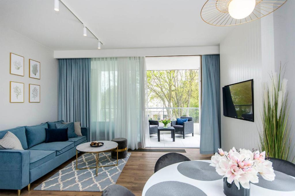 a living room with a blue couch and a table at Blue Rentyear Apartments in Gdańsk