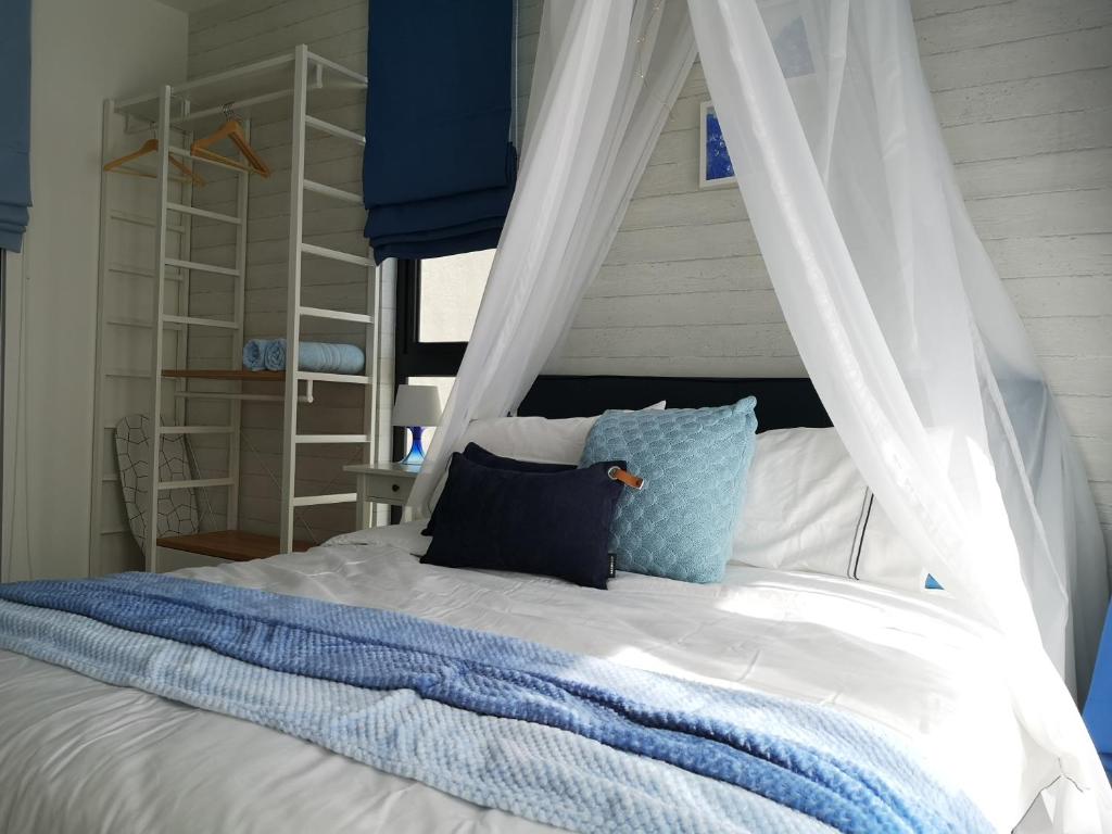 1 dormitorio con cama con dosel y almohada azul en H2O Residences Marine Blue by ADDS, en Petaling Jaya