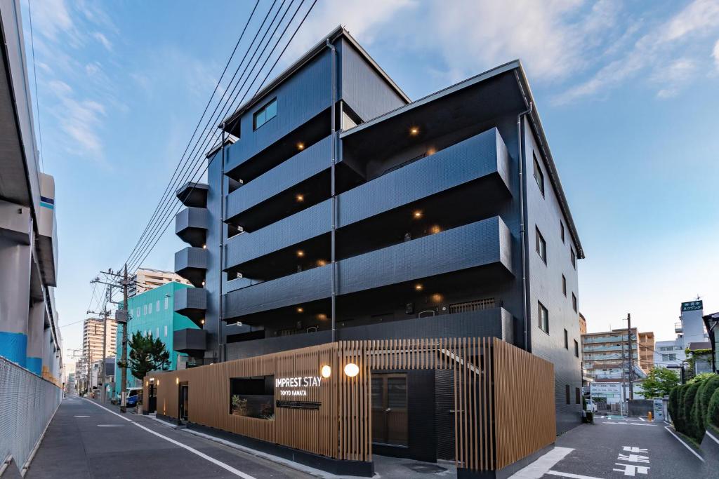 a tall black building with a gate on a street at IMPREST STAY Tokyo Kamata in Tokyo