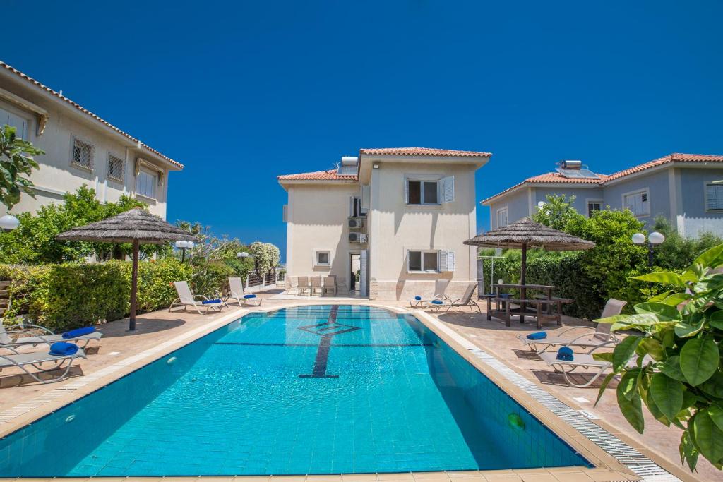 a swimming pool with chairs and umbrellas next to a building at Jason Villas in Protaras