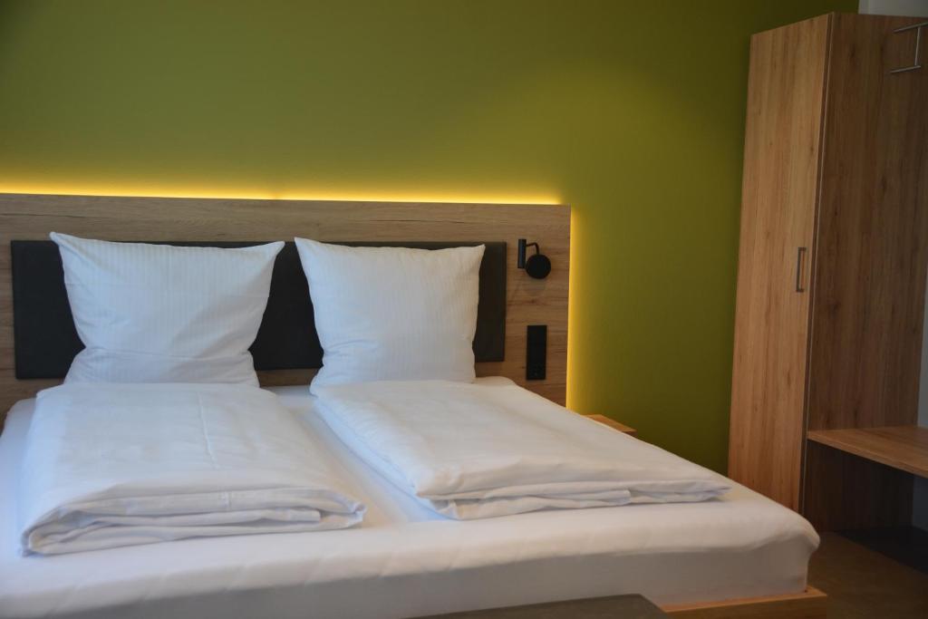 Weingut Bugner Meizelhof في Klein-Winternheim: سرير مع وسادتين بيضاء وجدار أخضر