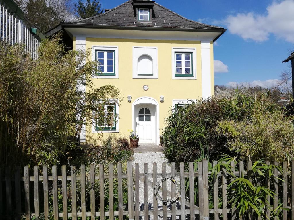 a yellow house with a white picket fence at Fancy Luxury Home In Former Tavern in Gmunden