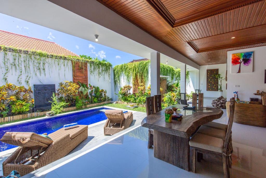 a living room with a pool and a table and chairs at MasBro ART Villas in Seminyak