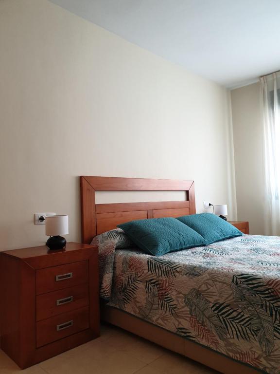 um quarto com uma cama e uma mesa de cabeceira com uma almofada azul em Apartamento Las Pontigas em Posada de Llanes