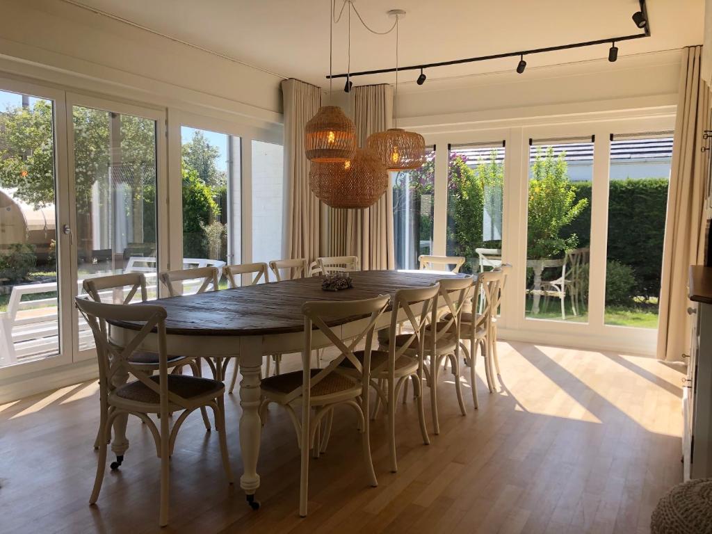 uma sala de jantar com uma grande mesa de madeira e cadeiras em Villa Zuid em De Haan