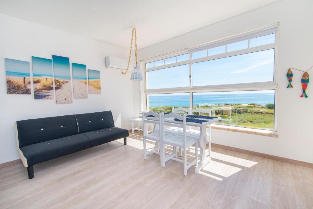 a living room with a couch and a table and a window at Casa dos Peixes in Armação de Pêra