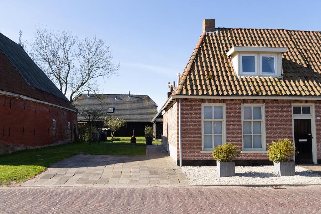 une maison en briques avec deux plantes en pot devant elle dans l'établissement Vissershuisje aan de waddenzee, à Paesens