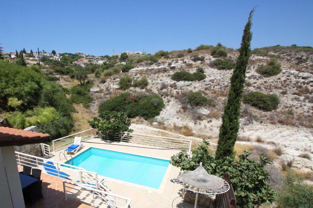 a house with a swimming pool next to a hill at Amoroza Villa in Pissouri