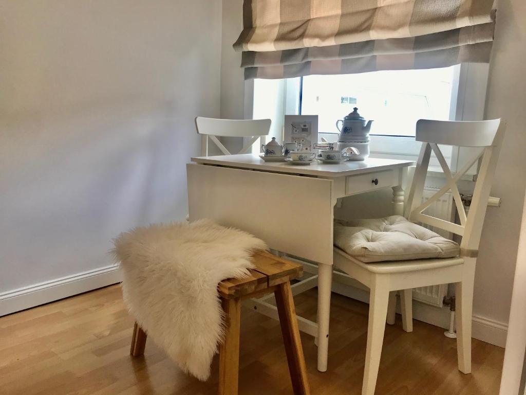 a desk with two chairs and a white table with a fur rug at Haus Meeresbrise Haus Karin in Norderney