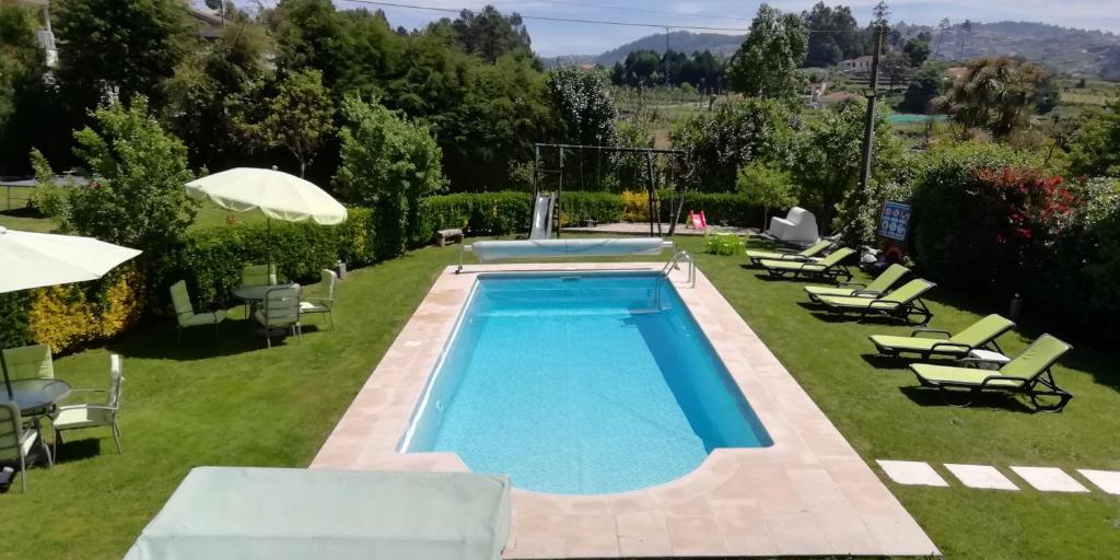 a swimming pool in a yard with chairs and umbrellas at My Portugal for All - Lousada Villa in Lousada