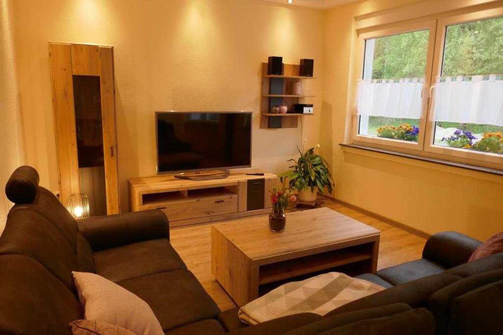 Suite Am Radweg في Pittenbach: غرفة معيشة مع أريكة وتلفزيون بشاشة مسطحة