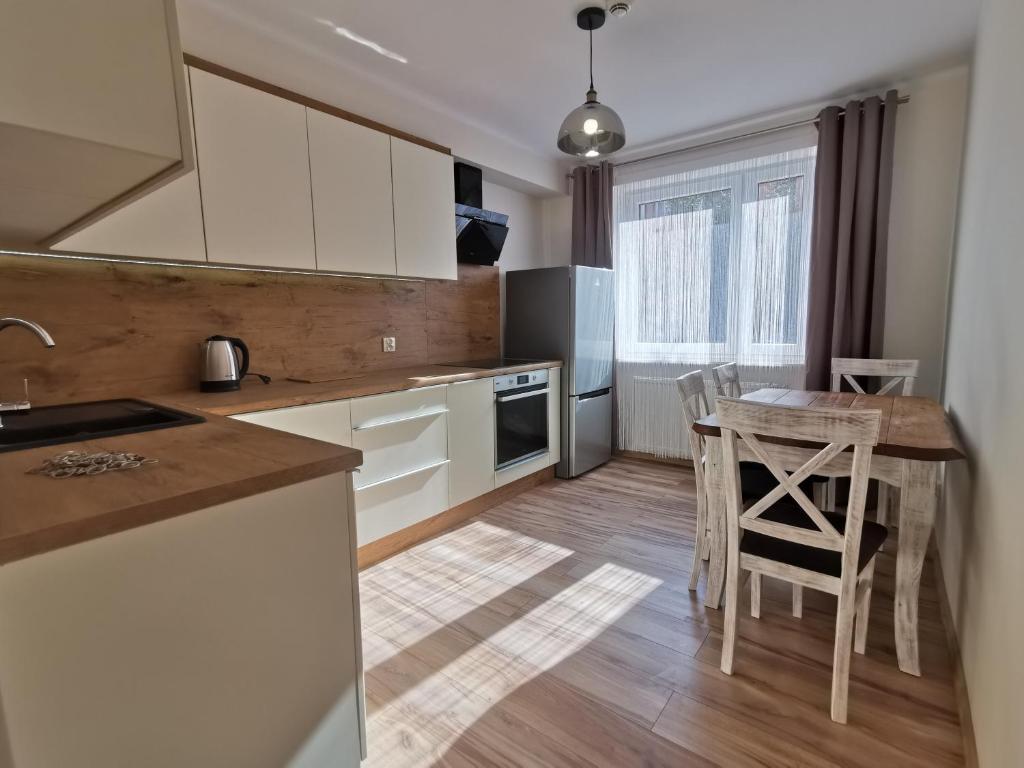 uma cozinha com armários brancos e uma mesa e cadeiras em Apartament KAKADU em Konin