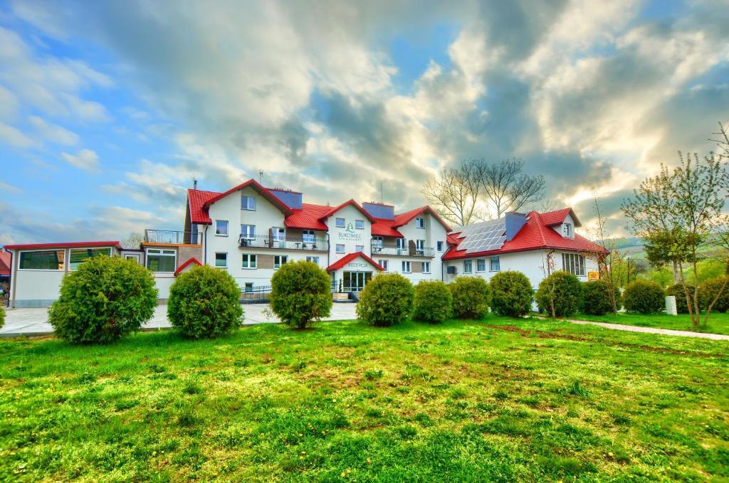 una gran casa con techos rojos en un césped verde en SPA & RESORT BUKOWIEC, en Polańczyk