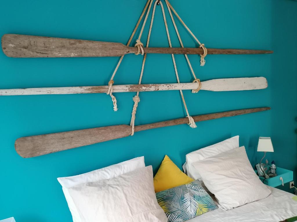 - une chambre dotée d'un mur bleu avec plusieurs éléments en bois flotté suspendus au-dessus d'un lit dans l'établissement Proche Le Pouldu, cadre verdoyant avec parking, à Clohars-Carnoët