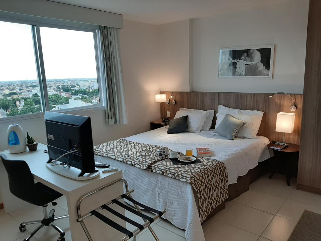 a hotel room with a bed and a desk with a computer at Flat pensado para sua tranquilidade e alegria in Campos dos Goytacazes