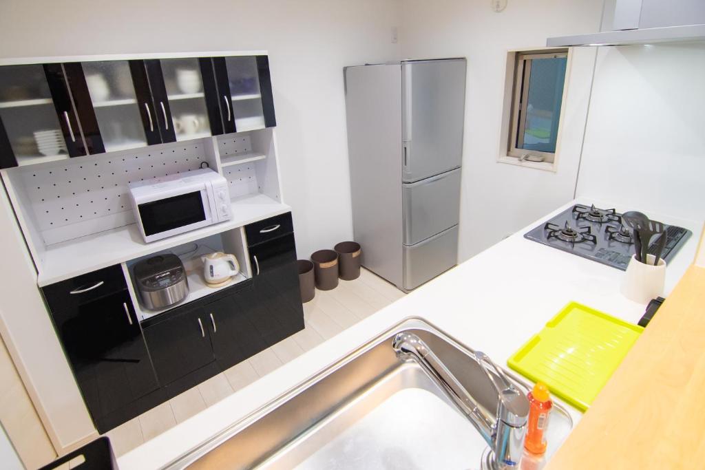 eine kleine Küche mit einer Spüle und einer Mikrowelle in der Unterkunft Convertel Honhaneda in Tokio