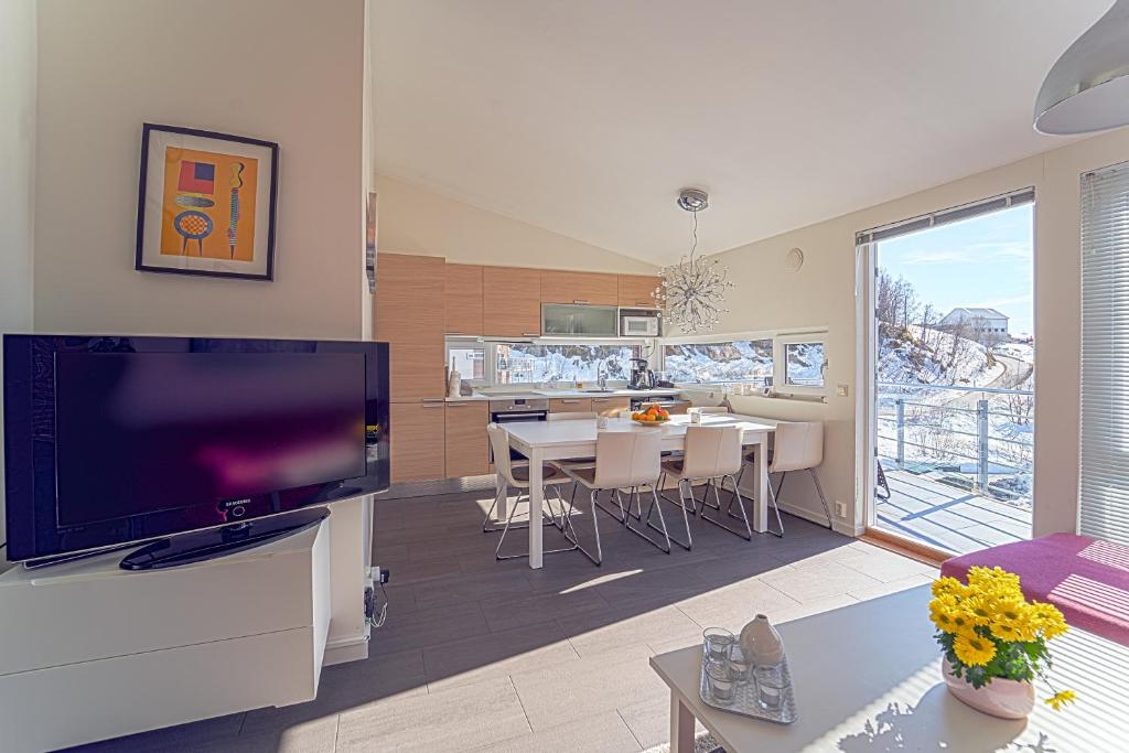 - un salon avec une grande télévision et une table avec des chaises dans l'établissement Three-Bedroom Apartment, à Tjørhom