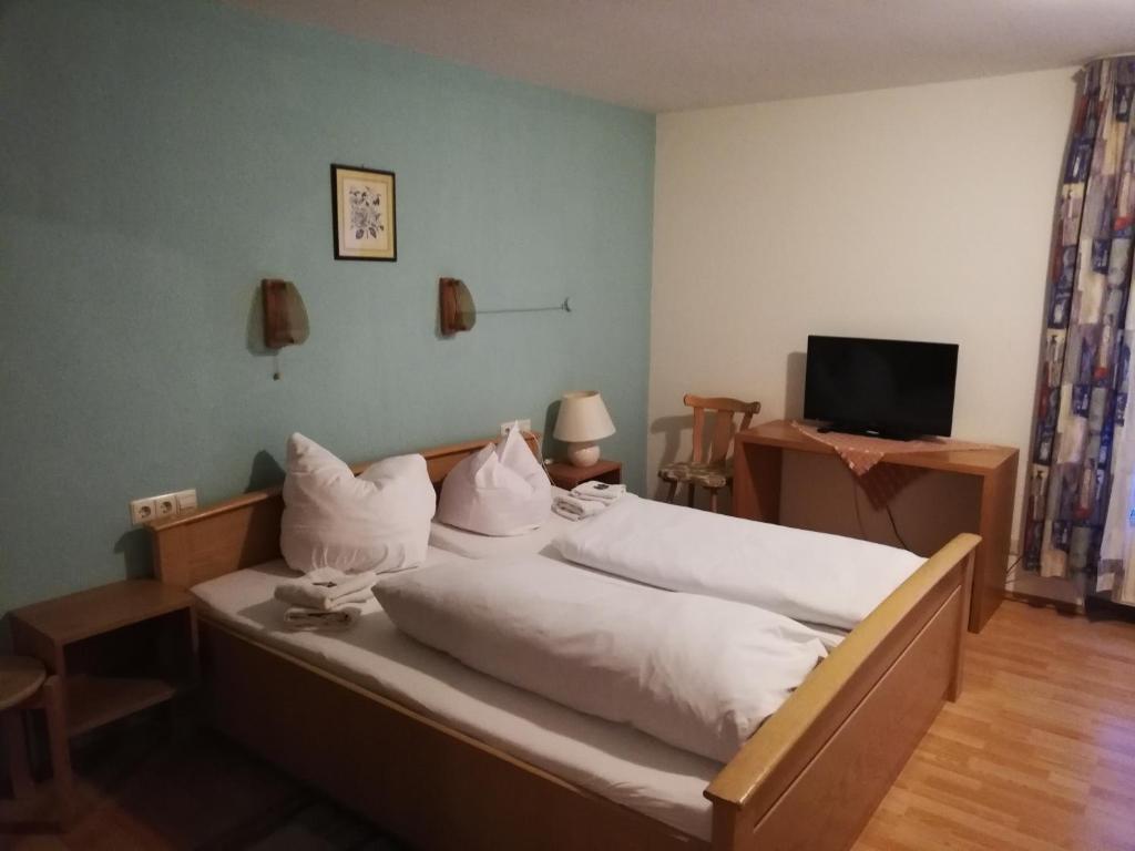 a bedroom with a bed with white sheets and pillows at Hotel Linde in Biberach-Ummendorf