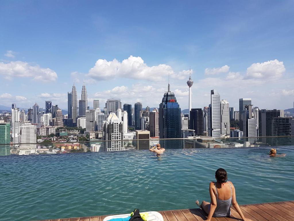 a woman sitting in a infinity pool overlooking a city at Regalia Residences KLCC Infinity Pool by 109 Suites in Kuala Lumpur