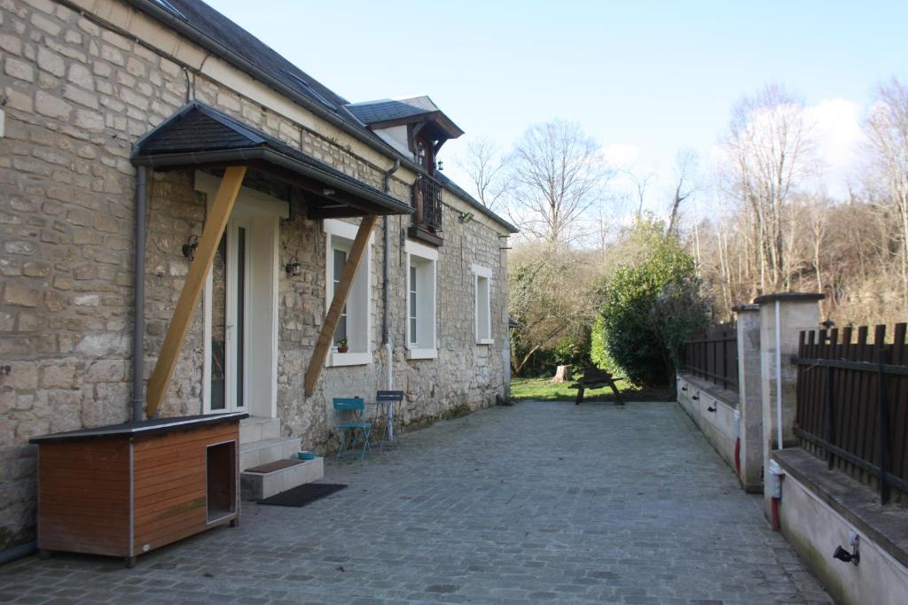 Casa de piedra con patio junto a un edificio en Chambre chez l'habitant Les Aubes du Vexin, en Nucourt