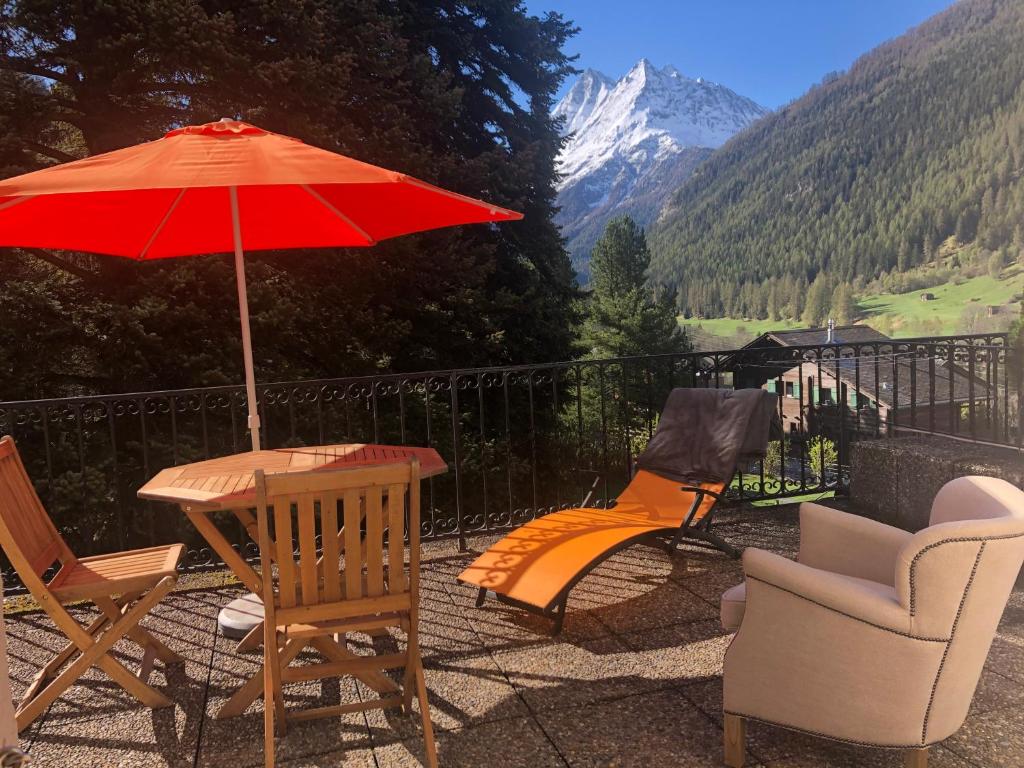 une terrasse avec une table, des chaises et un parasol dans l'établissement Au village d'Evolène, bel appartement avec terrasse, à Evolène