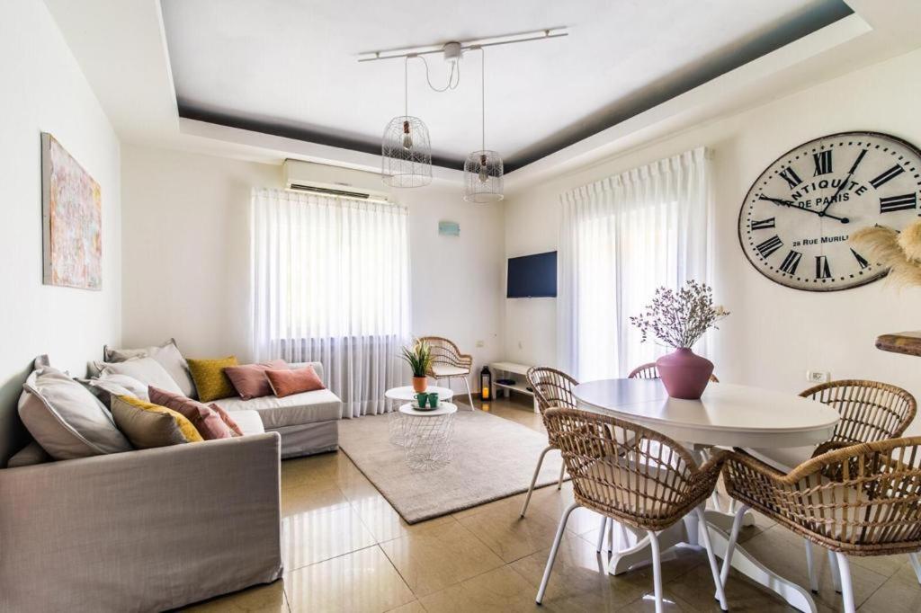 a living room with a table and a clock on the wall at Molho 2BR for 6 guests in Jerusalem