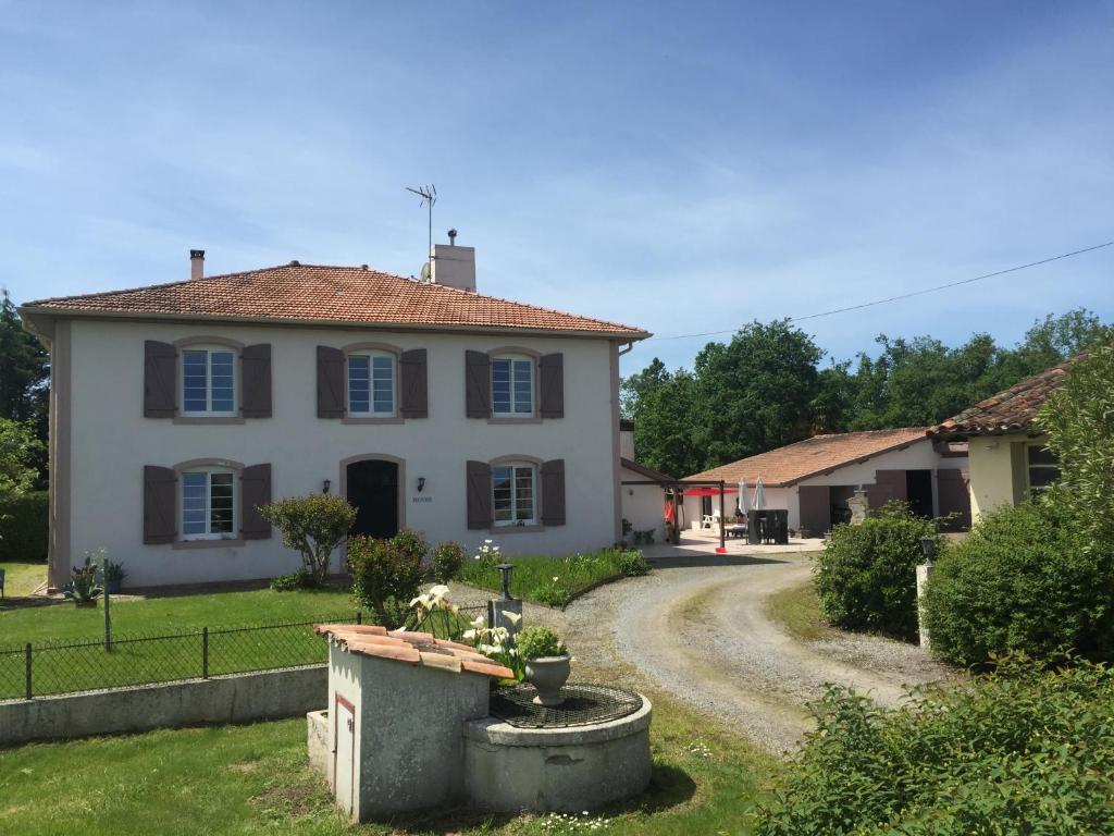 une grande maison blanche avec un chemin de terre dans l'établissement L'Intemporelle, à Ozourt