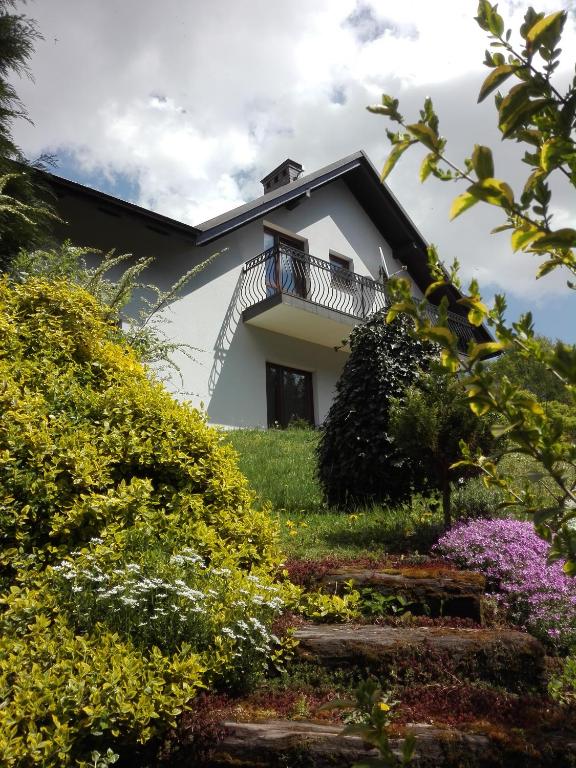 a white house with a balcony and some flowers at Apartamenty Leszczynowa 7 blisko Zatora in Spytkowice