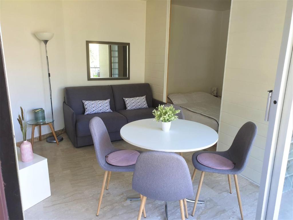 a living room with a table and chairs and a couch at Charmant appartement dans résidence avec piscine in Mandelieu-La Napoule