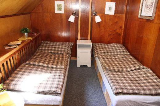 two beds in a room with wooden walls at Turistická Chata Pláně in Český Dub