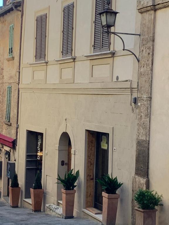 un edificio con due piante in vaso di fronte ad esso di Stefania Townhouse a Montepulciano