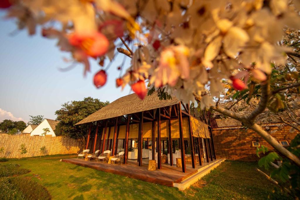 een tuinhuisje met banken in een tuin met een boom bij Roukh Kiri Khaoyai in Pak Chong