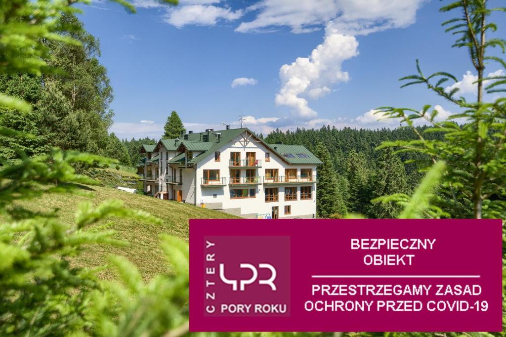 une maison sur une colline avec un panneau devant elle dans l'établissement 4 Pory Roku & Spa, à Krynica-Zdrój