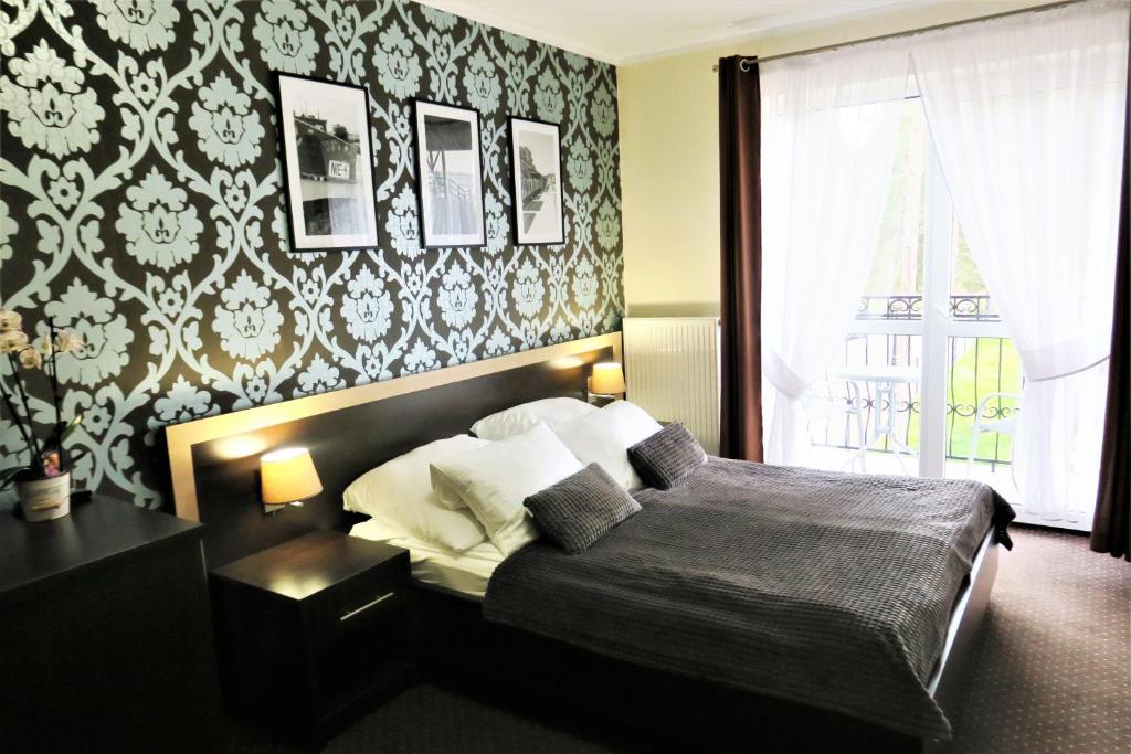 um quarto com uma cama e uma parede com papel de parede em Pensjonat Albatros Pogorzelica em Pogorzelica