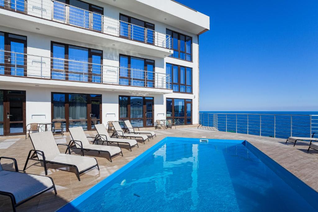 a swimming pool with chairs and a building at Sun Ray in Yalta