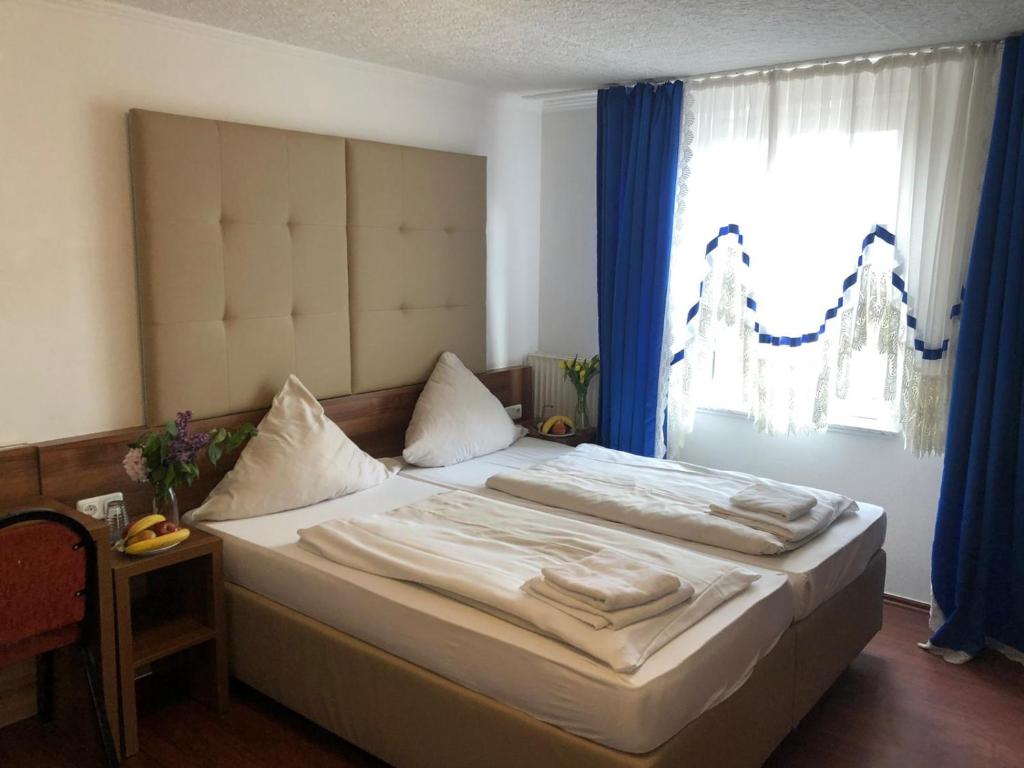 a bedroom with a bed with blue curtains and a window at Hotel Riede in Bremen