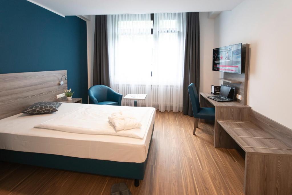 um quarto com uma cama, uma secretária e uma televisão em New Work Hotel Essen em Essen