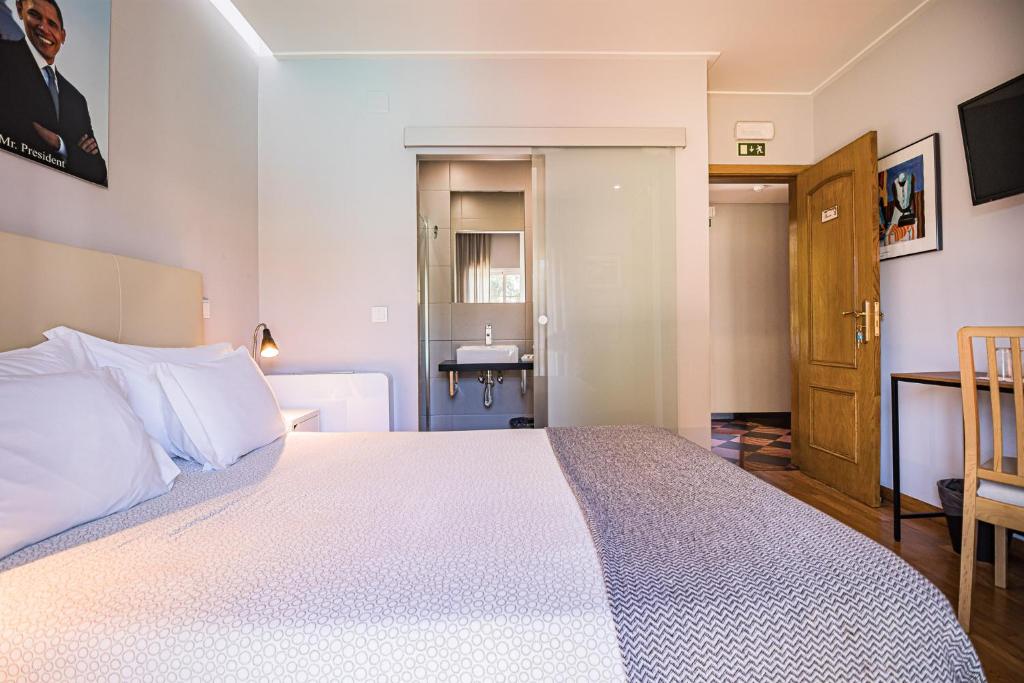 a bedroom with a large bed and a bathroom at Buganvilias Do Meco Guest house in Sesimbra