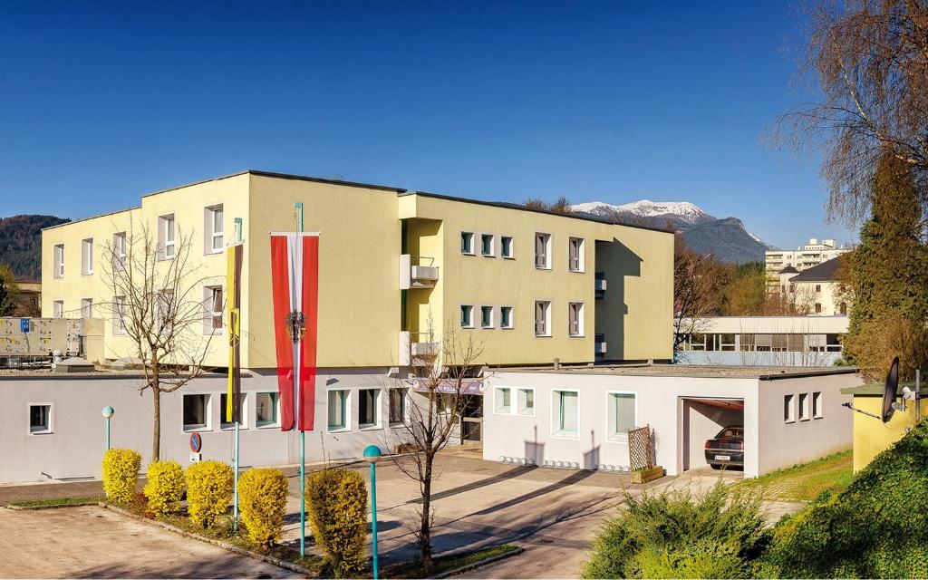 ein großes gelbes Gebäude mit weißen Gebäuden und Bergen in der Unterkunft Jugend- und Familiengästehaus Villach in Villach