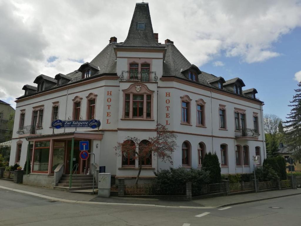 a white building with a pointed roof on a street at Cafe Zur Talsperre in Chemnitz